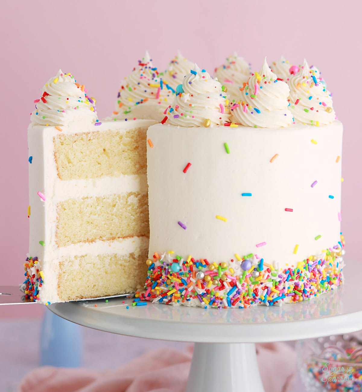 White celebration cake with colorful sprinkles and creamy frosting